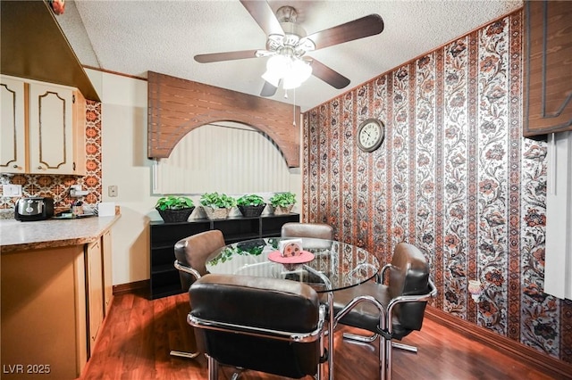 dining area with ceiling fan, dark hardwood / wood-style flooring, and a textured ceiling