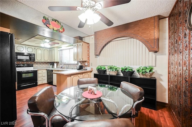 kitchen with backsplash, ceiling fan, sink, black appliances, and hardwood / wood-style flooring