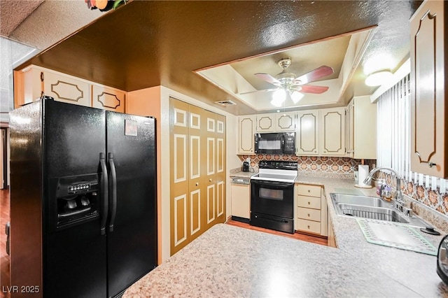 kitchen with kitchen peninsula, a raised ceiling, ceiling fan, sink, and black appliances