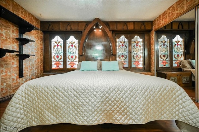 bedroom with wooden walls, wood-type flooring, and a textured ceiling