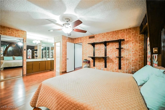 bedroom featuring a textured ceiling, ceiling fan with notable chandelier, and light hardwood / wood-style flooring