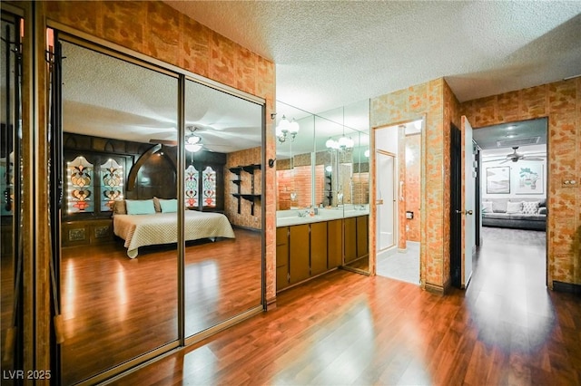 bedroom with connected bathroom, wood-type flooring, and a textured ceiling