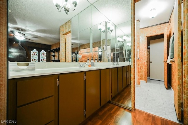 bathroom featuring ceiling fan with notable chandelier, a textured ceiling, vanity, and hardwood / wood-style flooring