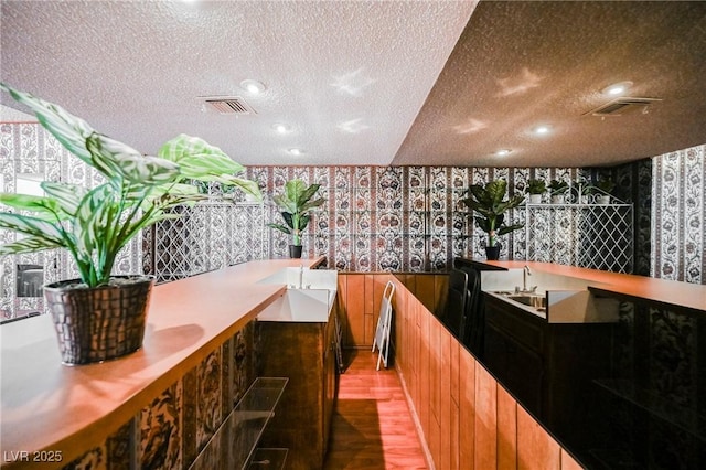 bar with wood-type flooring and a textured ceiling