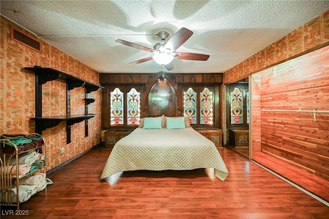 bedroom featuring ceiling fan, wood walls, and wood-type flooring