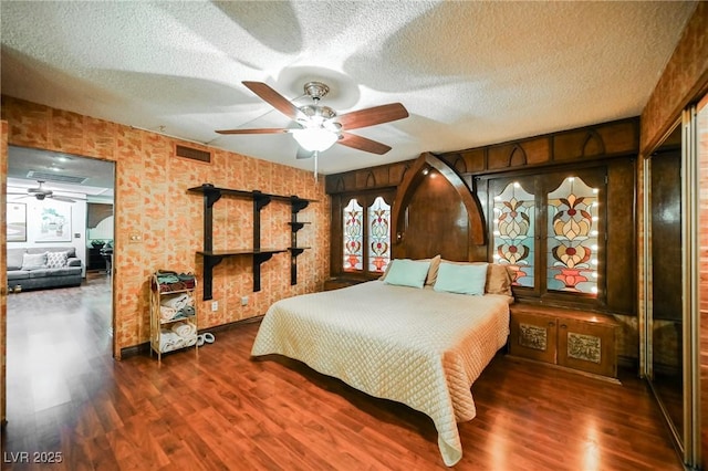 bedroom with ceiling fan, dark wood-type flooring, and a textured ceiling