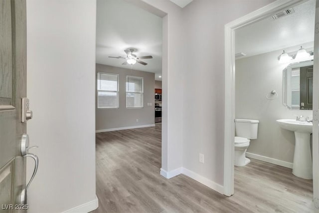 bathroom with ceiling fan, toilet, wood-type flooring, and sink