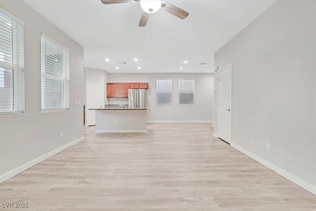 unfurnished living room featuring ceiling fan and light hardwood / wood-style flooring