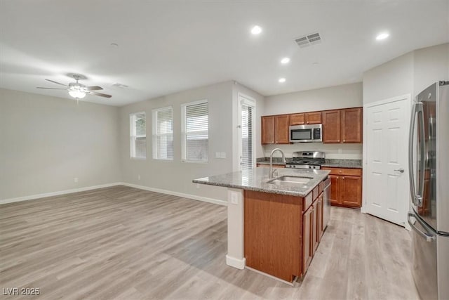 kitchen featuring a kitchen island with sink, sink, ceiling fan, light hardwood / wood-style floors, and stainless steel appliances