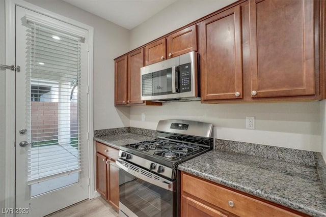 kitchen with dark stone counters, stainless steel appliances, and light hardwood / wood-style floors