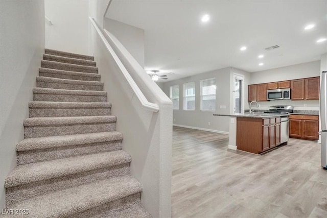 stairs with ceiling fan, hardwood / wood-style floors, and sink