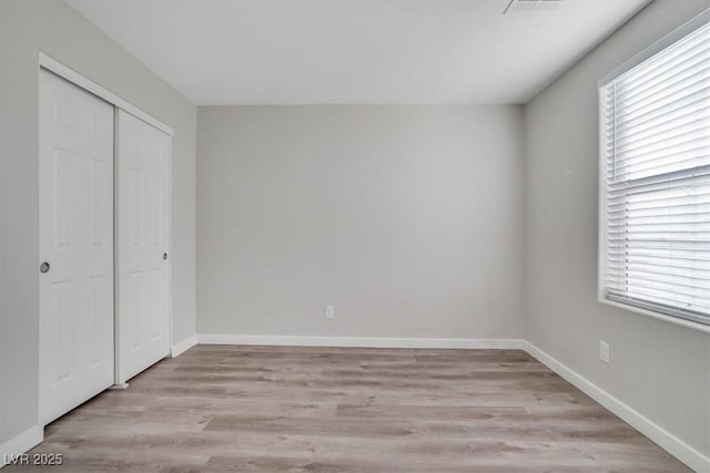 unfurnished bedroom featuring a closet, light hardwood / wood-style flooring, and multiple windows