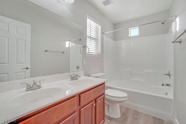 full bathroom featuring hardwood / wood-style flooring, vanity, shower / bathtub combination, and toilet