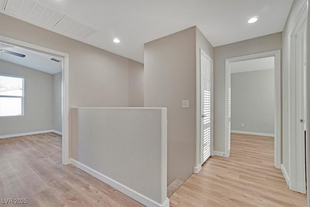 hall with lofted ceiling and light hardwood / wood-style flooring