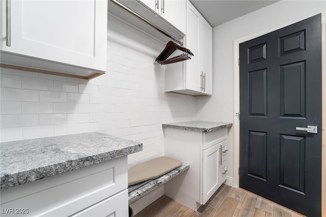 kitchen featuring light stone countertops, backsplash, and white cabinetry