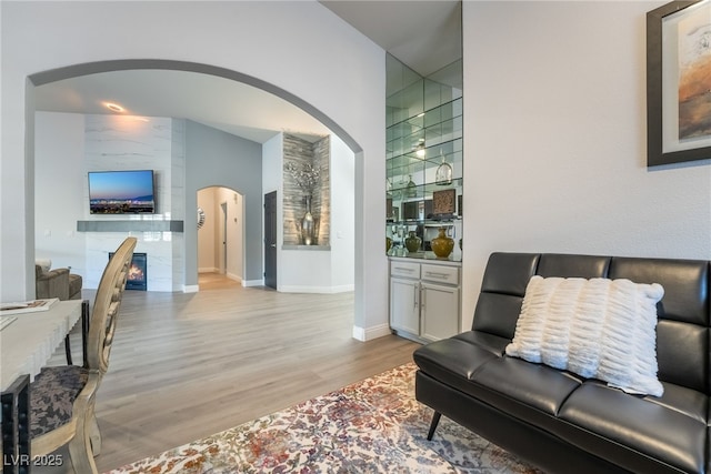 living room featuring a tile fireplace, light hardwood / wood-style flooring, and lofted ceiling