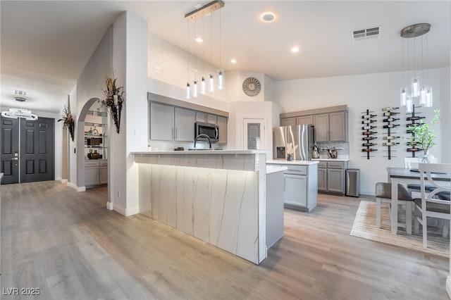 kitchen featuring decorative backsplash, an island with sink, hanging light fixtures, and appliances with stainless steel finishes