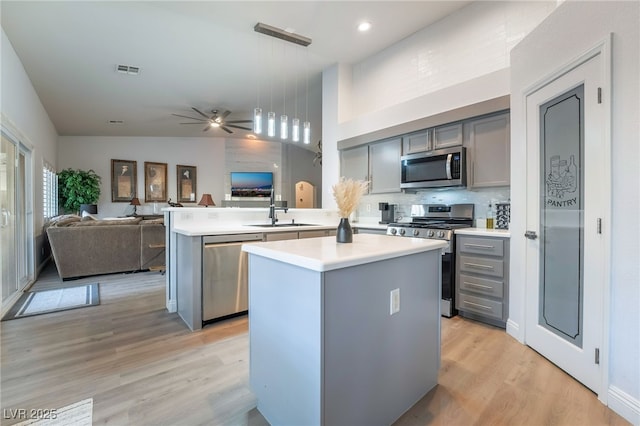 kitchen with gray cabinets, kitchen peninsula, a kitchen island, and stainless steel appliances