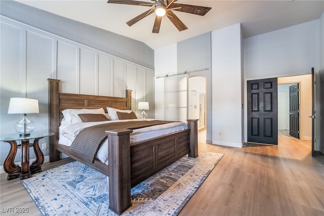 bedroom with ceiling fan, light hardwood / wood-style floors, and lofted ceiling