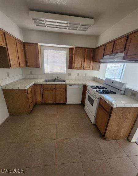 kitchen with tile counters, white appliances, sink, and light tile patterned floors