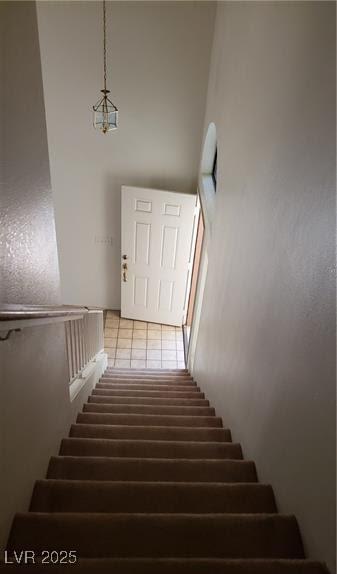 staircase with a high ceiling and tile patterned floors