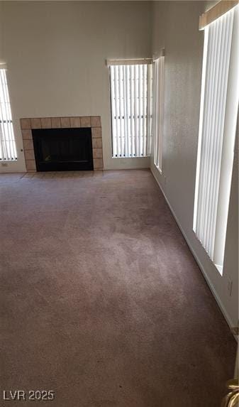 unfurnished living room featuring a tiled fireplace and carpet floors