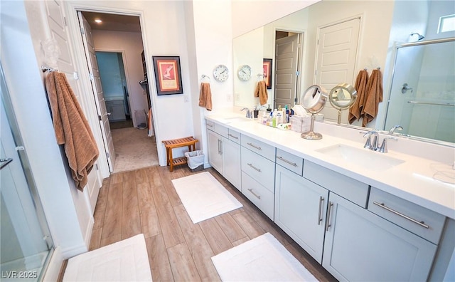 bathroom with hardwood / wood-style floors, vanity, and a shower with shower door