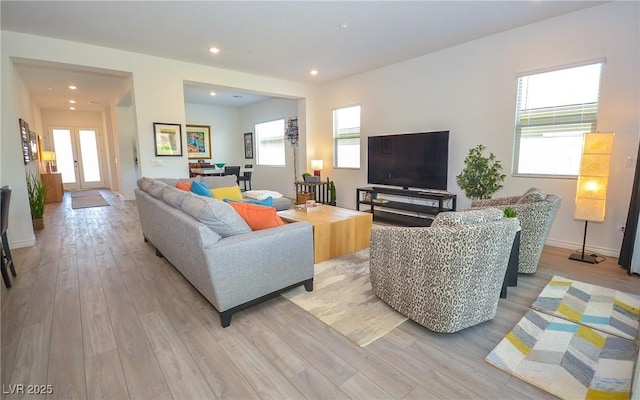 living room featuring french doors, light wood-type flooring, and plenty of natural light