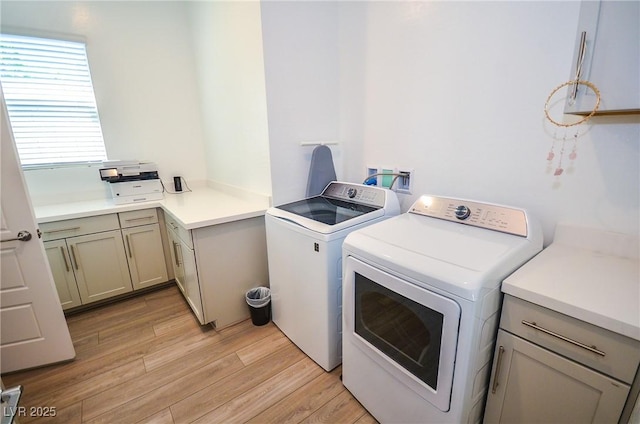 laundry area featuring cabinets, light wood-type flooring, and separate washer and dryer