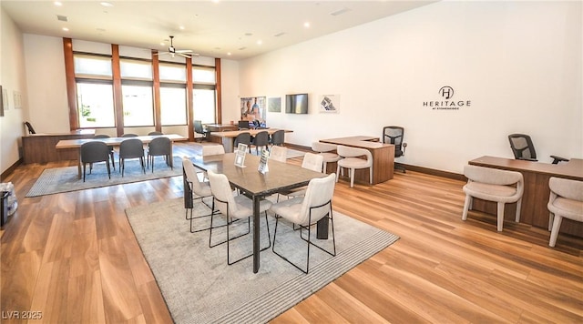 dining area with a towering ceiling, light hardwood / wood-style floors, and ceiling fan