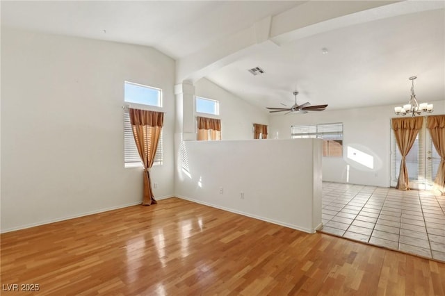 empty room with vaulted ceiling with beams, ceiling fan with notable chandelier, and light hardwood / wood-style floors