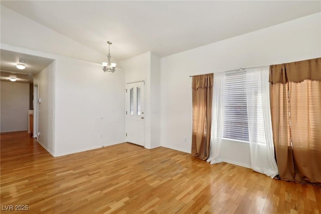 unfurnished room with lofted ceiling, light wood-type flooring, and a notable chandelier