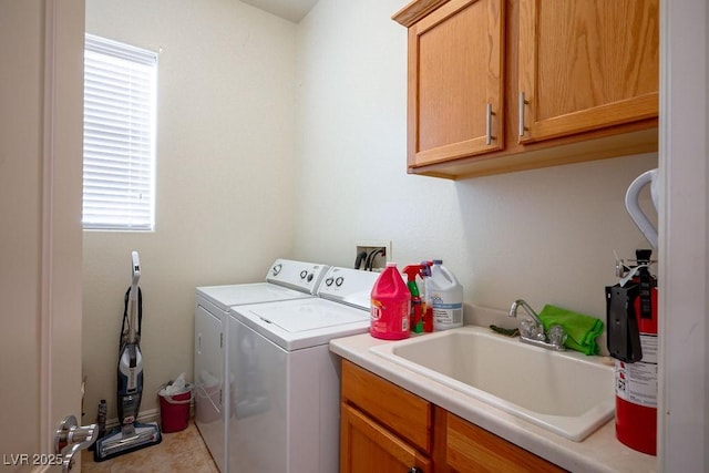 laundry area with cabinets, washing machine and clothes dryer, and sink