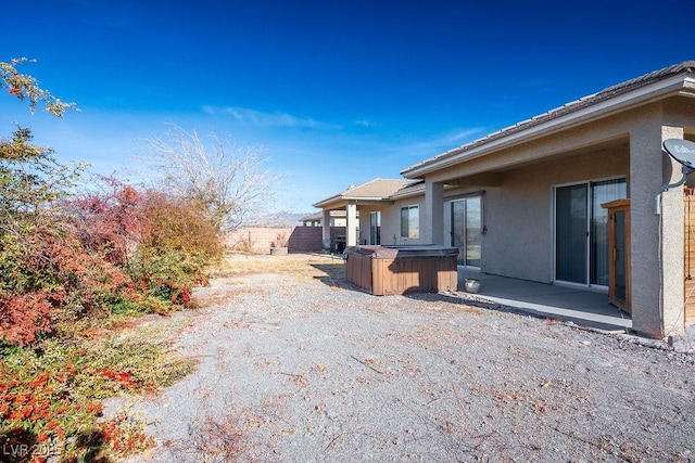 view of property exterior with a patio and a hot tub