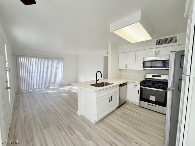 kitchen with kitchen peninsula, stainless steel appliances, white cabinetry, and sink