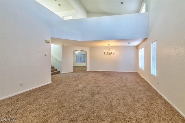 unfurnished room featuring carpet floors, a high ceiling, and an inviting chandelier