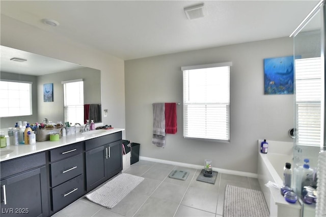 bathroom with a tub to relax in, a wealth of natural light, tile patterned floors, and vanity