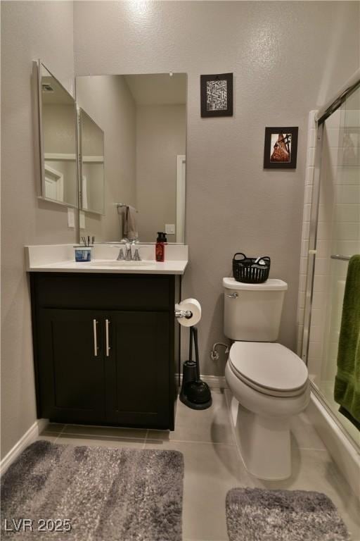 bathroom with tile patterned flooring, vanity, toilet, and a shower with shower door