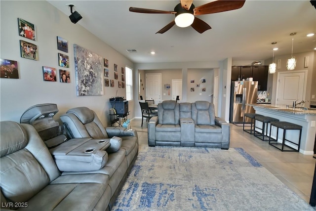 tiled living room featuring ceiling fan and sink