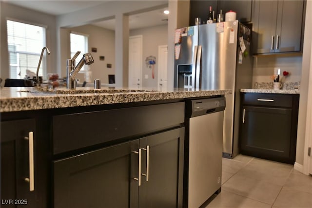 kitchen with light stone counters, dishwasher, light tile patterned flooring, and sink