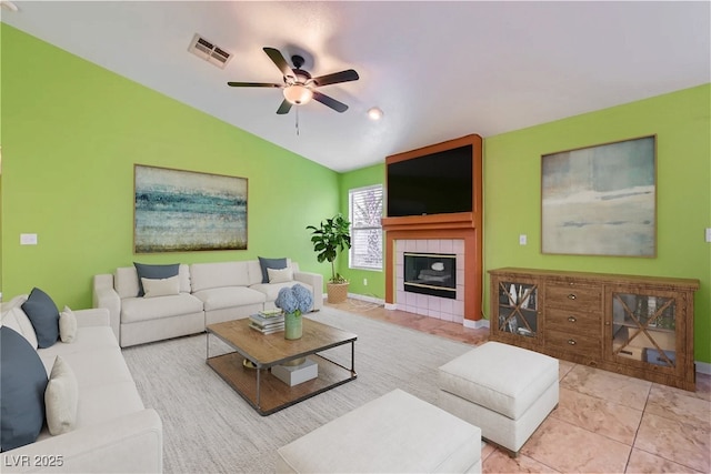 tiled living room with ceiling fan, a fireplace, and lofted ceiling