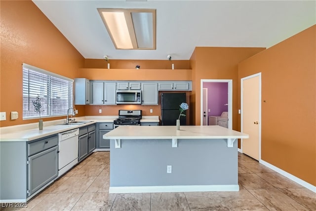 kitchen with washer and clothes dryer, a kitchen breakfast bar, sink, a kitchen island, and stainless steel appliances