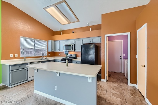 kitchen with lofted ceiling, sink, appliances with stainless steel finishes, a breakfast bar area, and washing machine and clothes dryer