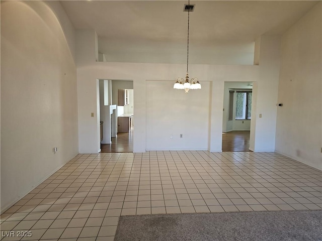 tiled empty room featuring an inviting chandelier