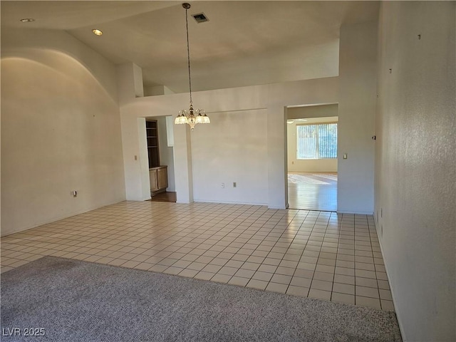 spare room featuring tile patterned floors, high vaulted ceiling, and a chandelier