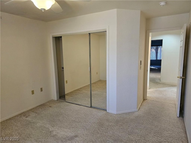 unfurnished bedroom with ceiling fan, a closet, and light carpet