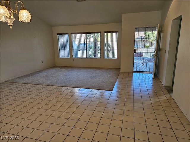 tiled spare room with a notable chandelier