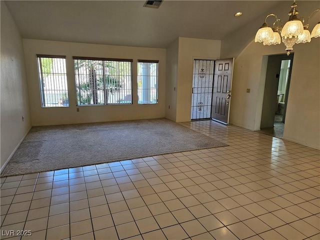 tiled spare room with a chandelier