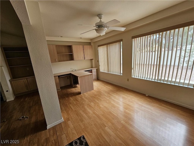 kitchen featuring ceiling fan, dishwasher, built in desk, and light hardwood / wood-style flooring