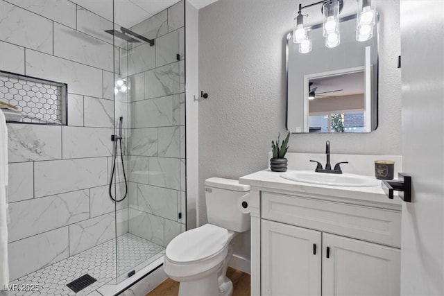 bathroom with a tile shower, vanity, and toilet